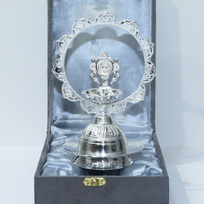 Silver deepak with intricate design in a box on a light gray background